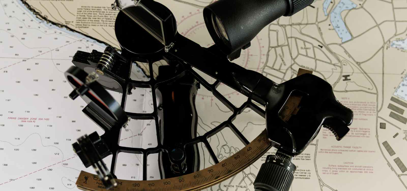 A sextant lying on top of a nautical chart.