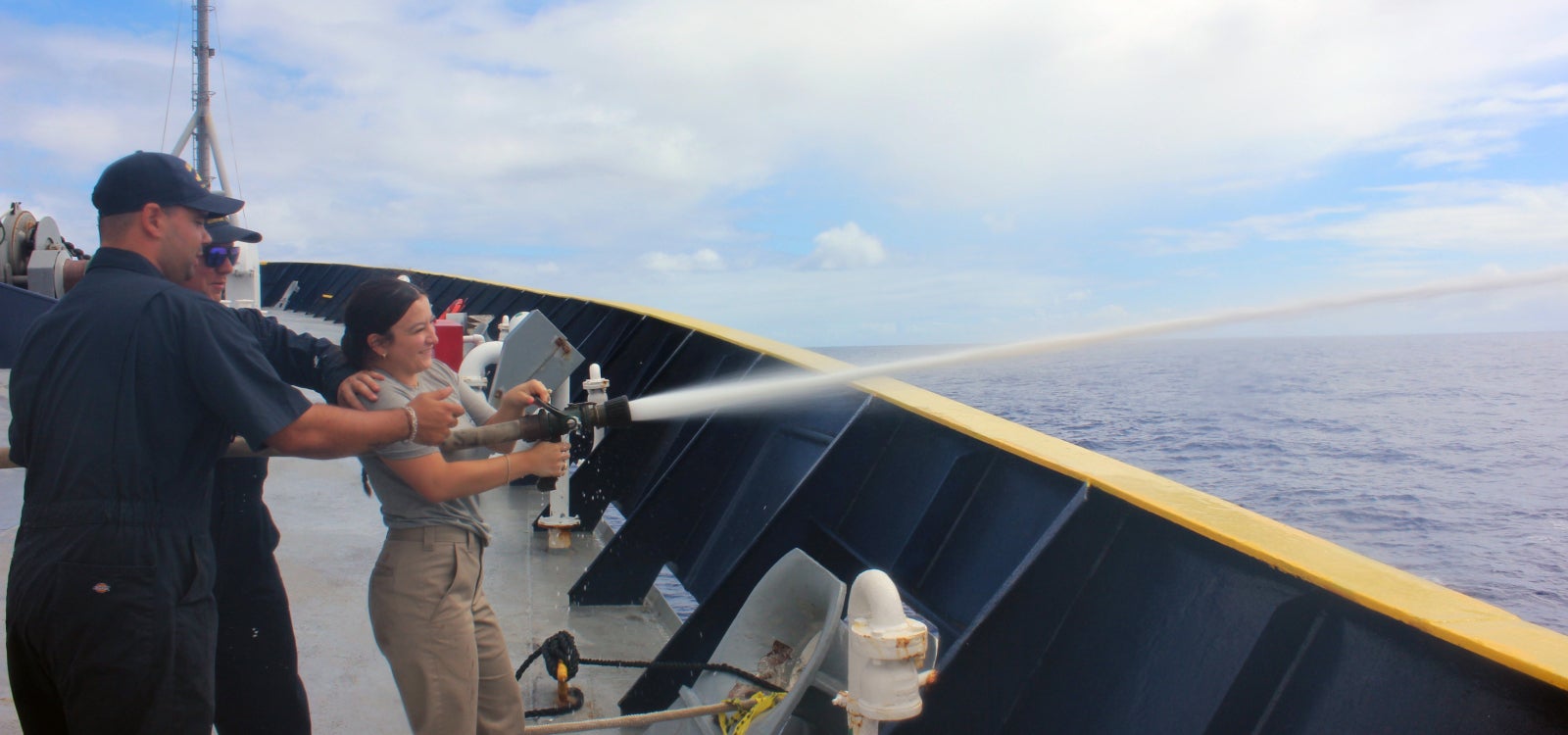 Cadet Gia Espejo using a water canon on the deck of Training Ship Golden Bear.