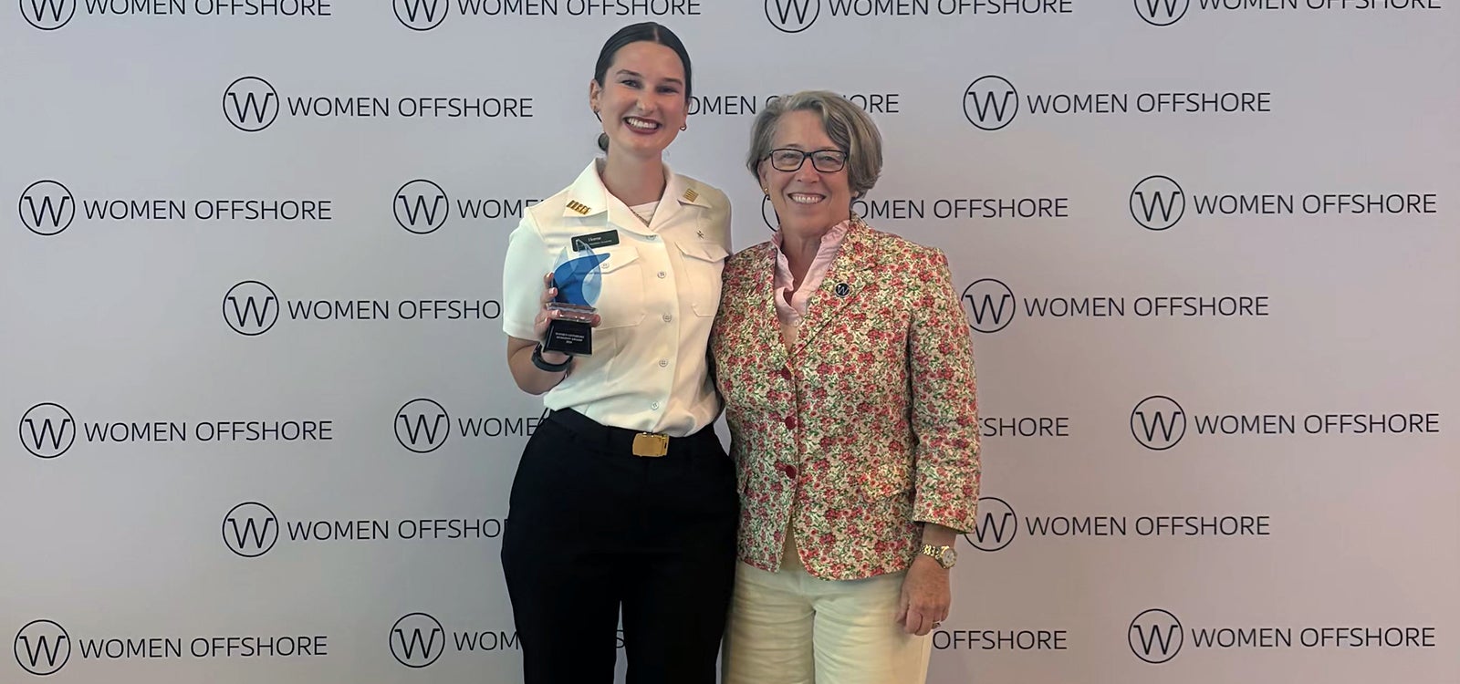 Bella Horne standing with her award and another person at an awards ceremony.