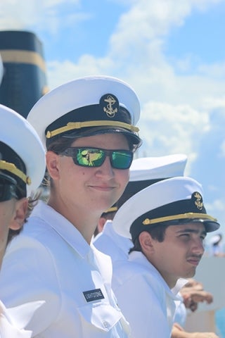 A cadet in uniform and sunglasses smiles at the camera