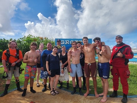A group of students pos in swim and dive gear in Saipan