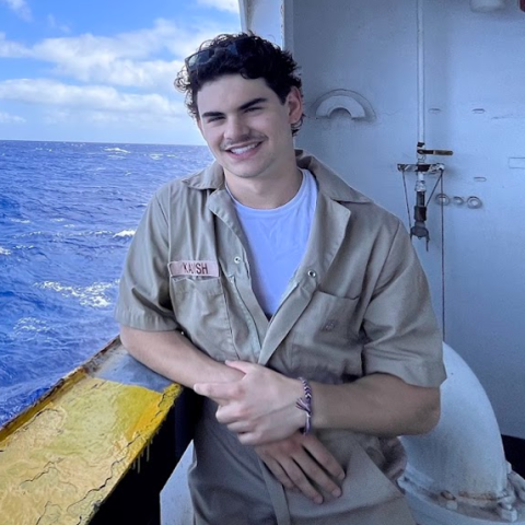 A headshot of Cadet Elijah Kadish aboard Training Ship Golden Bear with the ocean in the background.