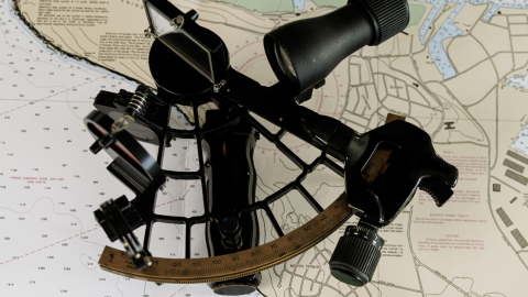 A sextant lying on top of a nautical chart.