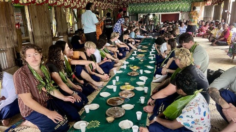 Cadets and crew share breakfast with residents of Vuisiga Village, seated on the floor as part of a traditional communal meal.