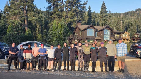The Cal Poly Maritime Academy SCUBA club standing for a photo on the roadside with cabins and trees in the background.