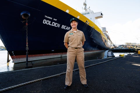 Capt. Samar B. Bannister standing in front of a docked Training Ship Golden Bear.