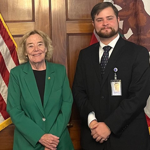 Liam Pogue-Hartwig and U.S. Rep. Zoe Lofgren (CA-18) standing in a room with flags behind them.