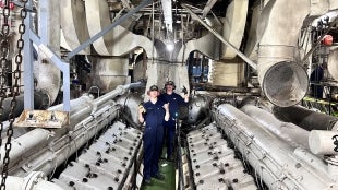 Two cadets pose in the working of the ship
