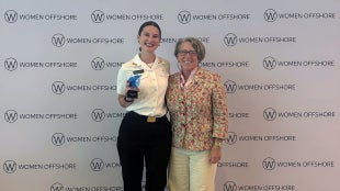 Bella Horne standing with her award and another person at an awards ceremony.