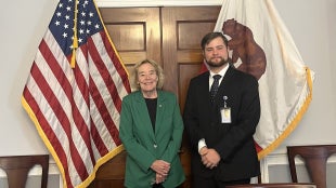 Liam Pogue-Hartwig and U.S. Rep. Zoe Lofgren (CA-18) standing in a room with flags behind them.