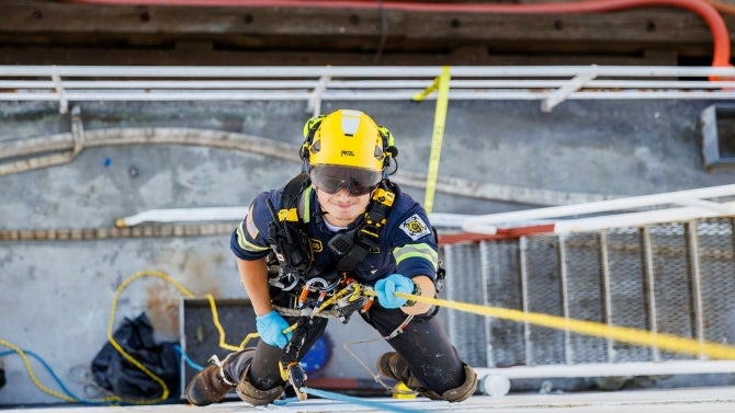 Student climbing up the side of a ship