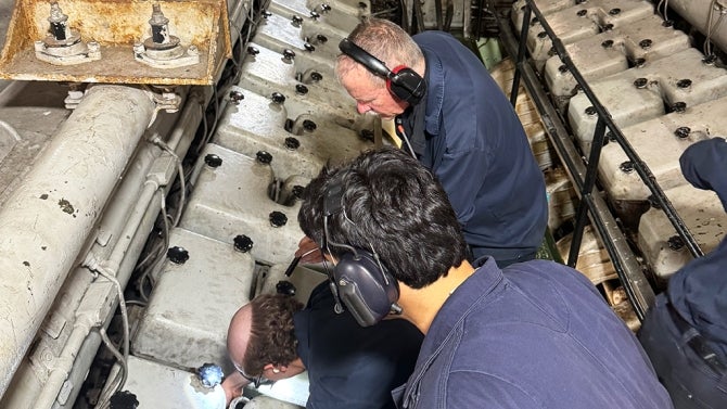 Students with instructor work on ship components