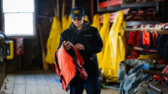A cadet dons a life preserver aboard ship