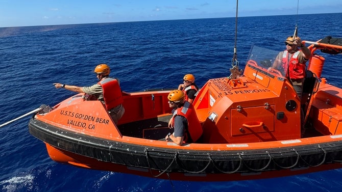 Students aboard a boat participate in man overboard drill