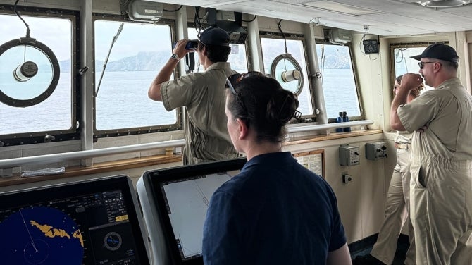 Maritime student looks out at sea with binoculars