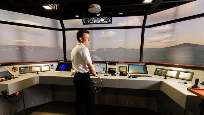 Student looks out to sea from ship control panel