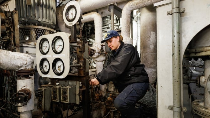 A Cal Poly Maritime Academy cadet working in the engine room.